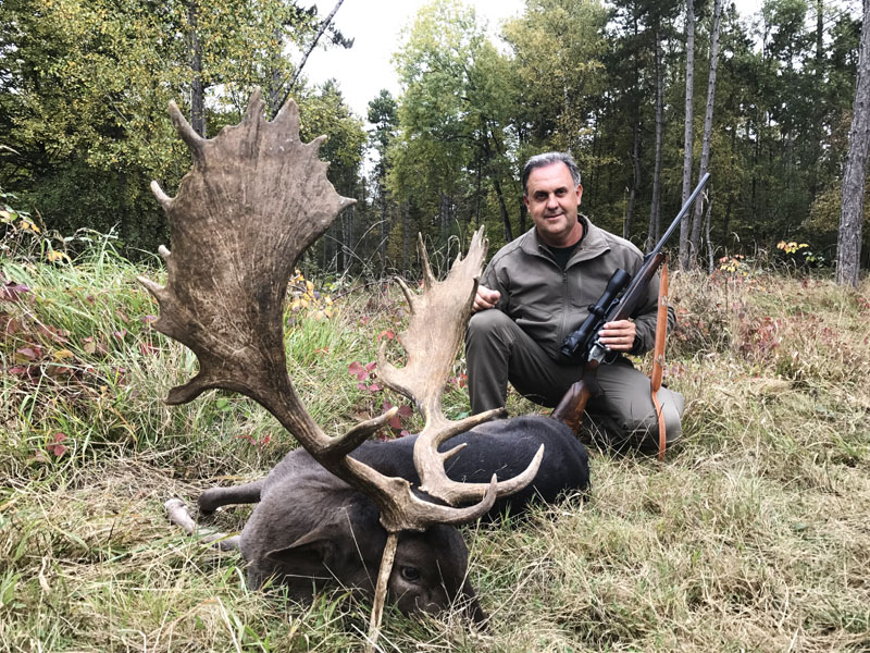Hunter with a big black fallow deer trophy, hunting in France